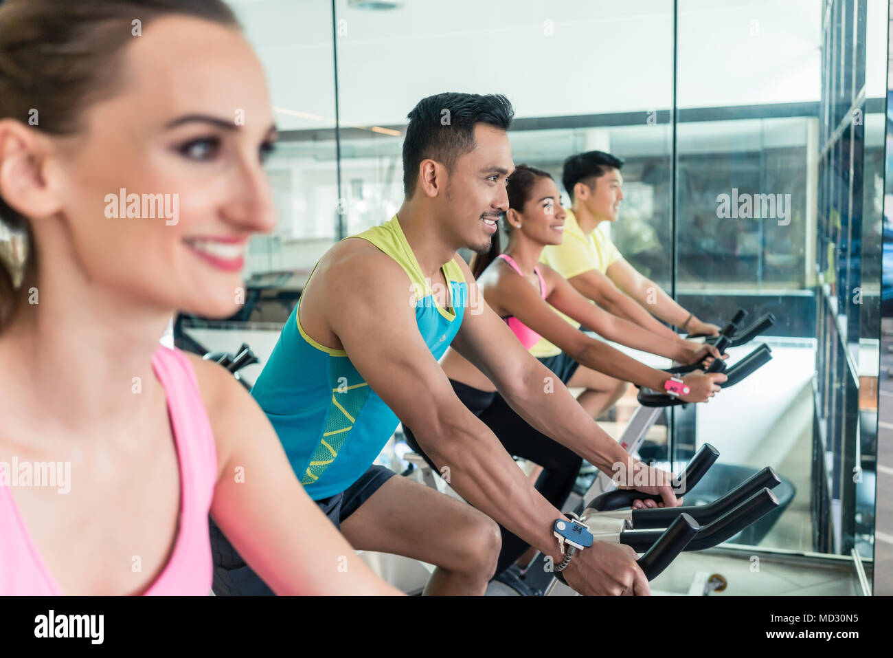 Beautiful fit woman smiling during workout at indoor cycling group class Stock Photo