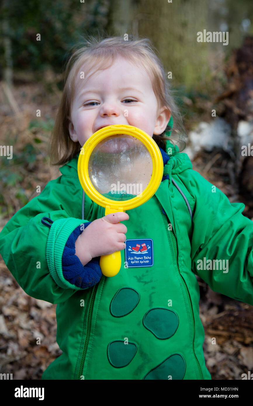A toddler with a large magnifying glass outdoors, UK Stock Photo
