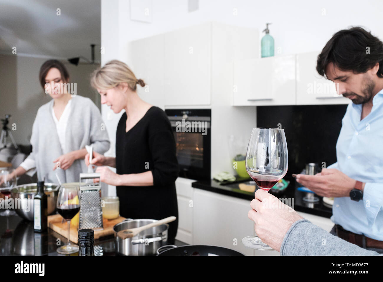 Selective focus.Group of friends casually snacking on a selection of food  and drinking red wine,while laughing and enjoying themselves. Stock Photo