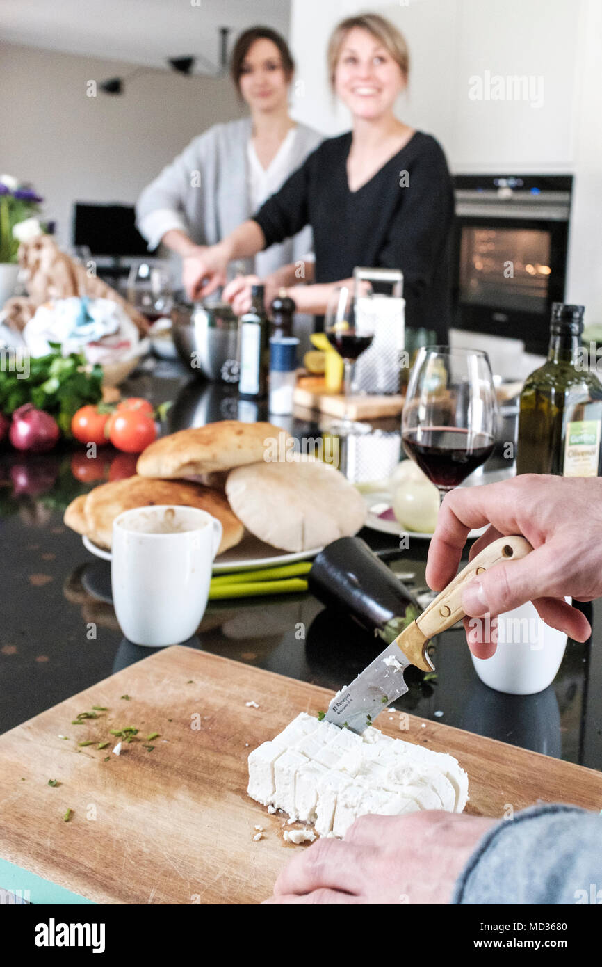 Preparing fetta cheese.Group of friends casually snacking on a selection of food while laughing and enjoying themselves. Stock Photo