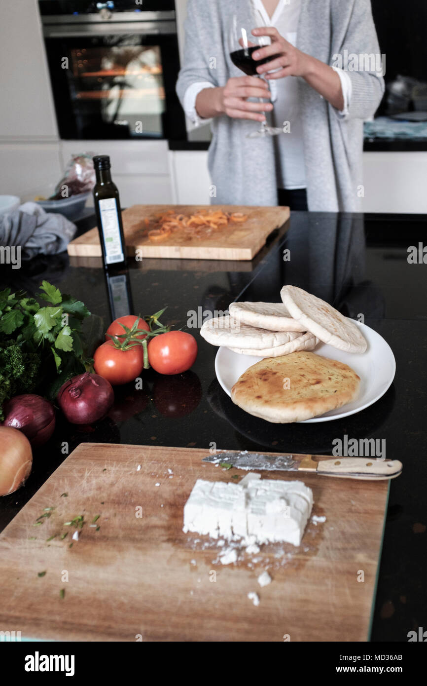 Flat bread ,and fetta cheese.Woman having a glass of red wine while preparing a healthy vegetarian meal-selective focus Stock Photo
