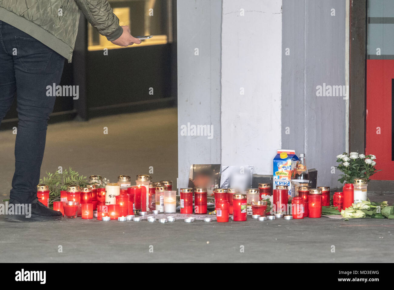 18 April 2018, Passau, Germany: A passerby photgraphs candles and flowers in front of an underground pedestrian passageway. According to an autopsy report by the police, the boy suffocated on his own blood during the fight an underground pedestrian passageway. Photo: Armin Weigel/dpa Stock Photo