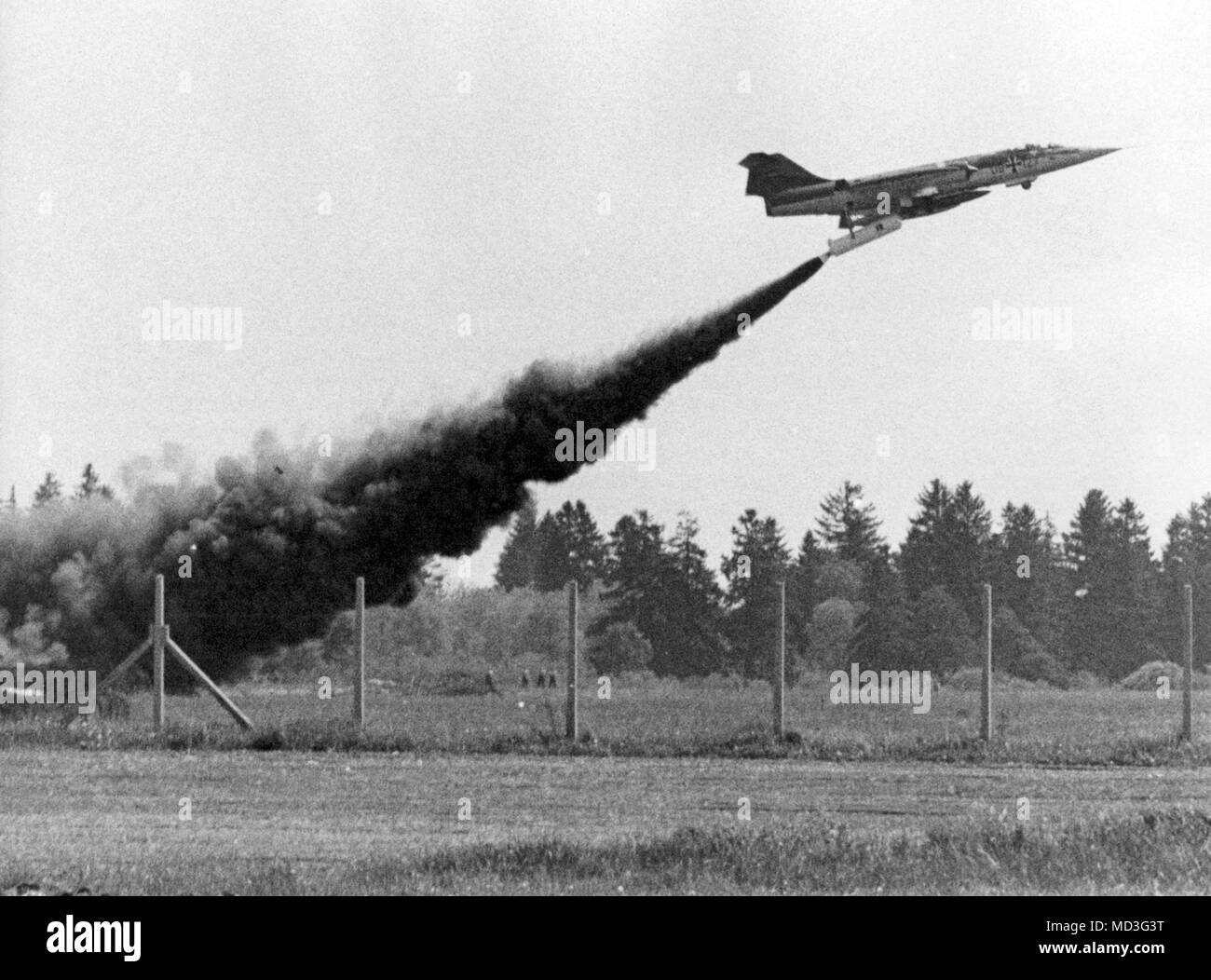 The rocket starfighter shortly after the start on 18.05.1966 on the airbase in the Bavarian camp Heel. The burned rocket under the machine is dropped after a full circle over the launch area. In front of 100 journalists, photographers and cameramen, the first rocket-launched Starfighter F 104 G was demonstrated on 18.05.1966 at the Bundeswehr airfield Lagerlechfeld near Augsburg. Underneath ear-droning drones, trailing behind a massive smoke tail, the starfighter lifted off from the launch pad mounted in a concrete bucket. In the cockpit sat the American test pilot Ed Brown. The rocket weighs Stock Photo