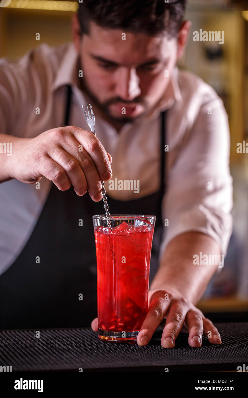 Barman in bar interior making non-alcoholic pomegranate cocktail Stock Photo