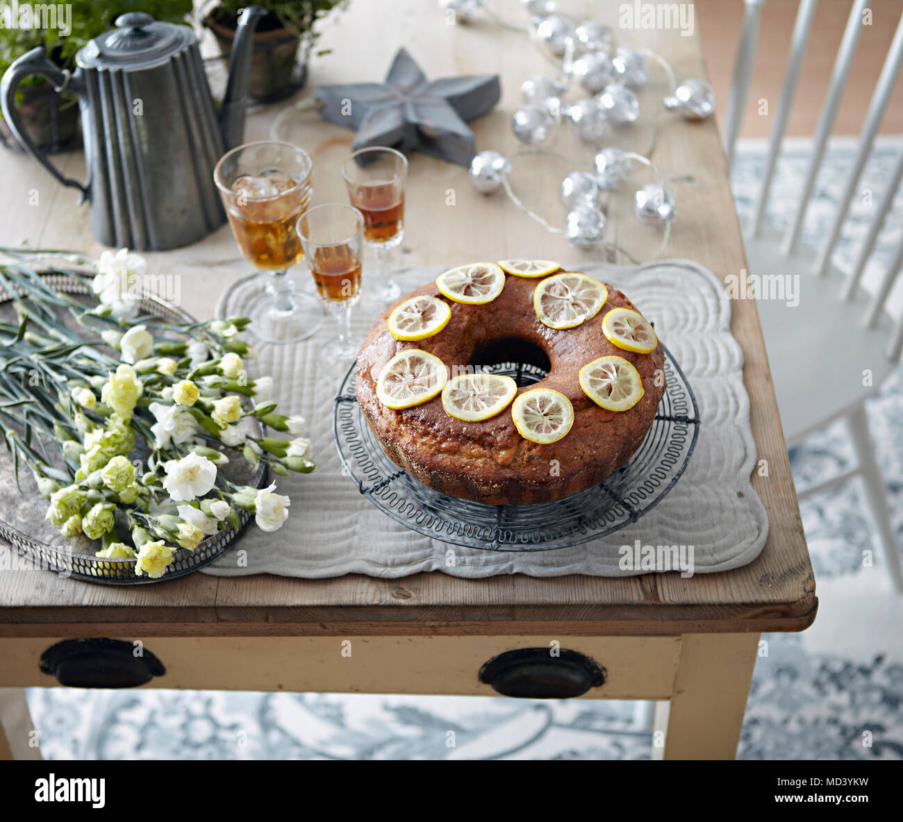 Table with bundt cake, flowers and drinks Stock Photo