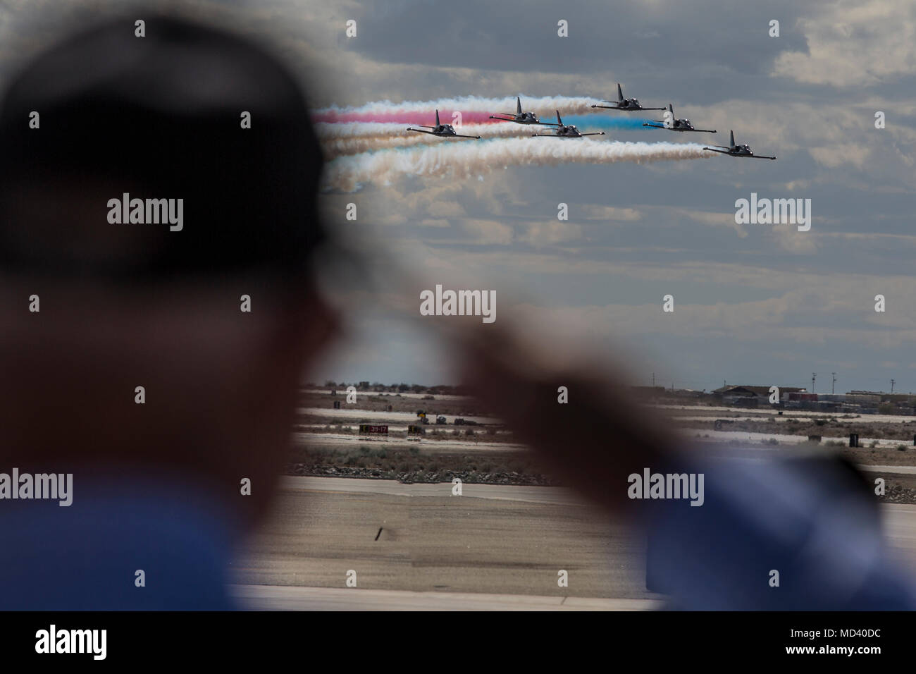 A spectator salutes as the 2018 Yuma Airshow headliner, The Patriots Jet Team, performs an acrobatic aerial display on the flight line of Marine Corps Air Station Yuma, Ariz., Saturday March 17, 2018. The Patriots Jet Team, are the largest civilian-owned aerobatic jet team in the western hemisphere, began with the vision of one person, Randy Howell. Fueled by a passion for aviation since childhood, it became Howell's mission to create a six-jet precision demonstration team that could entertain, inspire, and educate. The airshow is MCAS Yuma's only military airshow of the year and provides the  Stock Photo