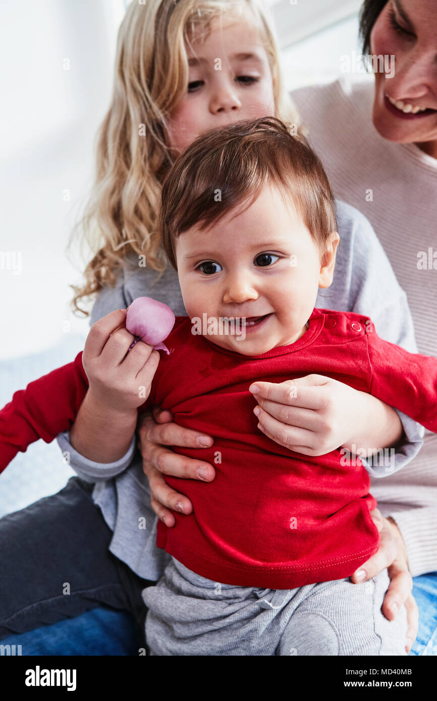 Mother sitting with two young daughters, smiling Stock Photo