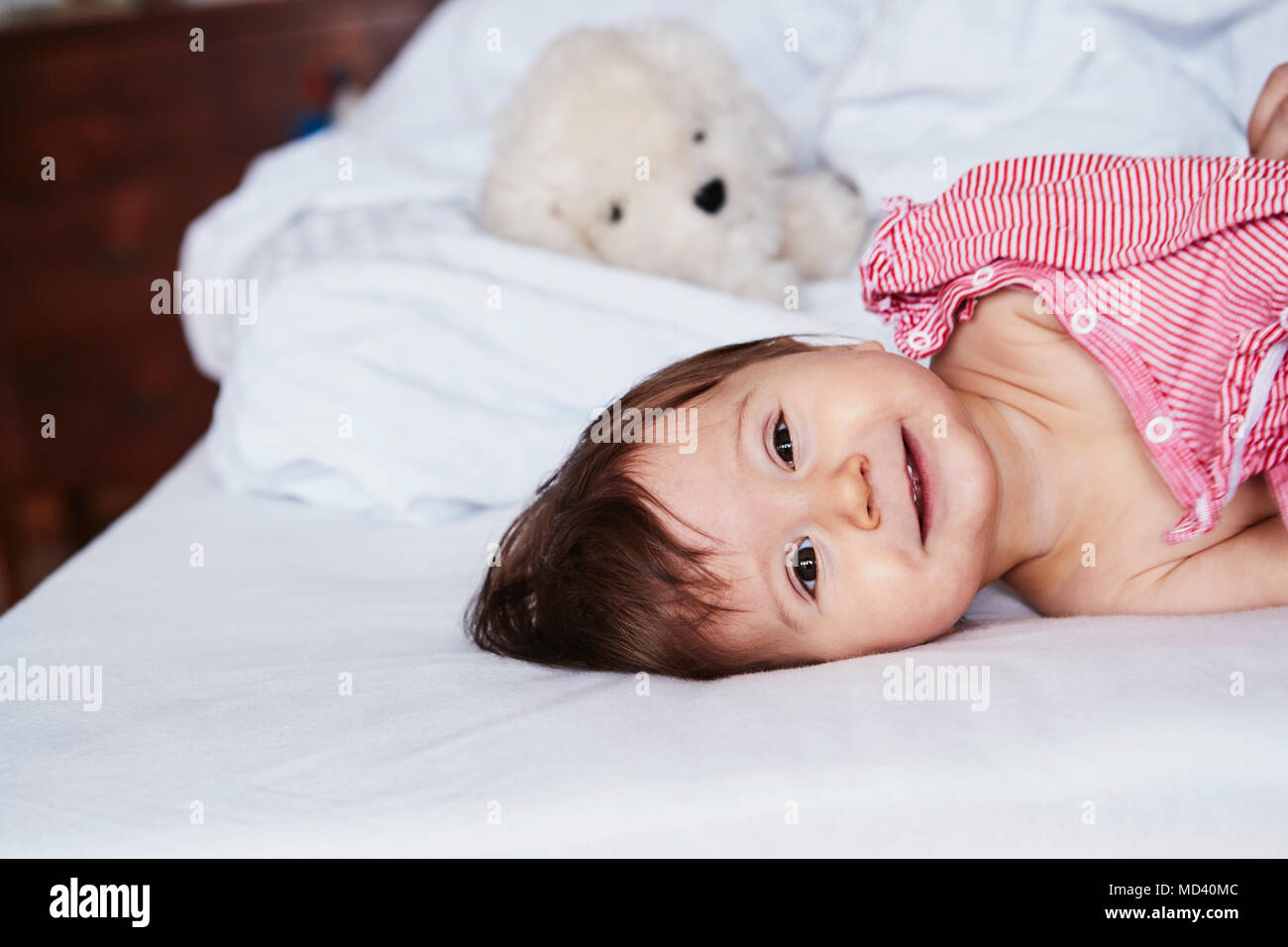 Portrait of baby girl lying on bed, smiling Stock Photo