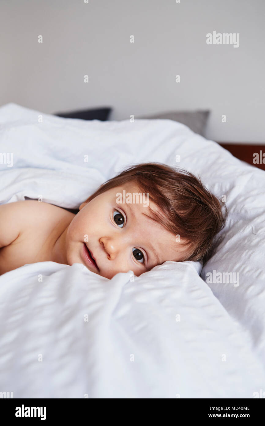 Portrait of baby girl lying on bed Stock Photo