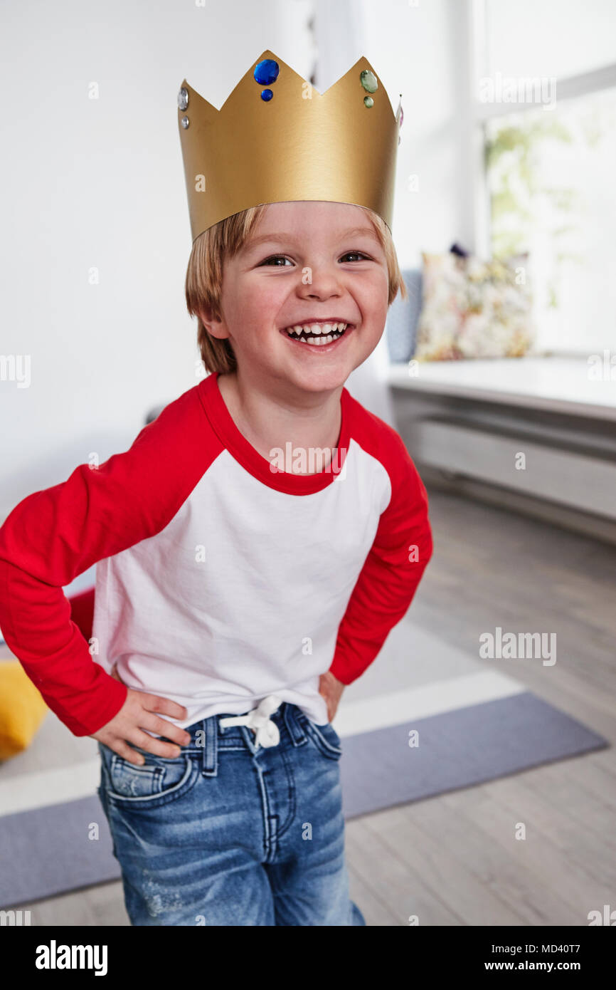 Portrait of young boy, wearing cardboard crown, smiling Stock Photo