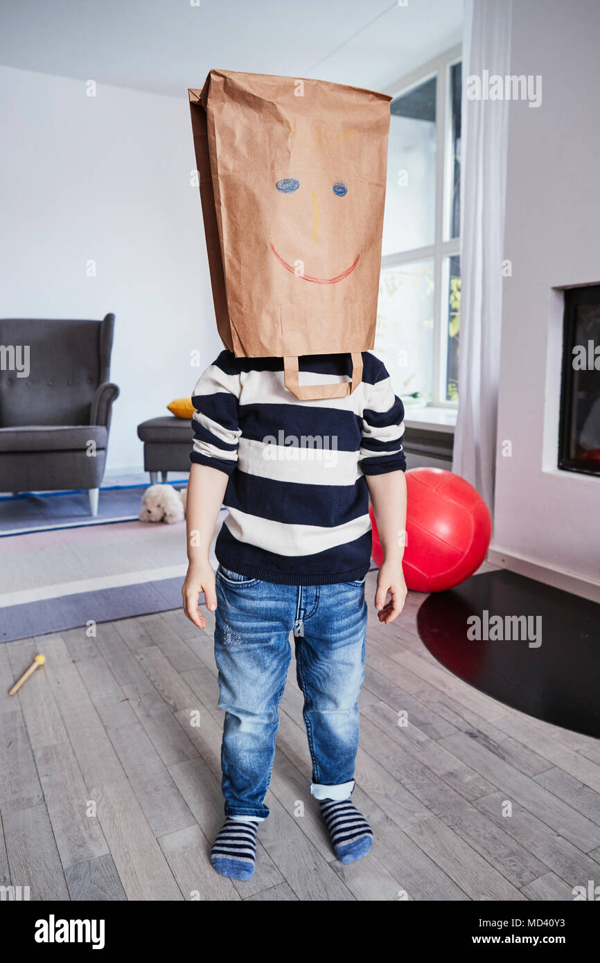 Portrait of young boy with brown bag on head, drawn face on brown bag Stock Photo