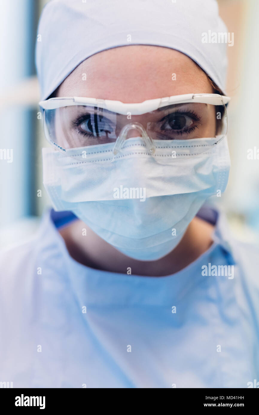 Portrait of female dentist, wearing surgical mask and protective eyewear, close-up Stock Photo