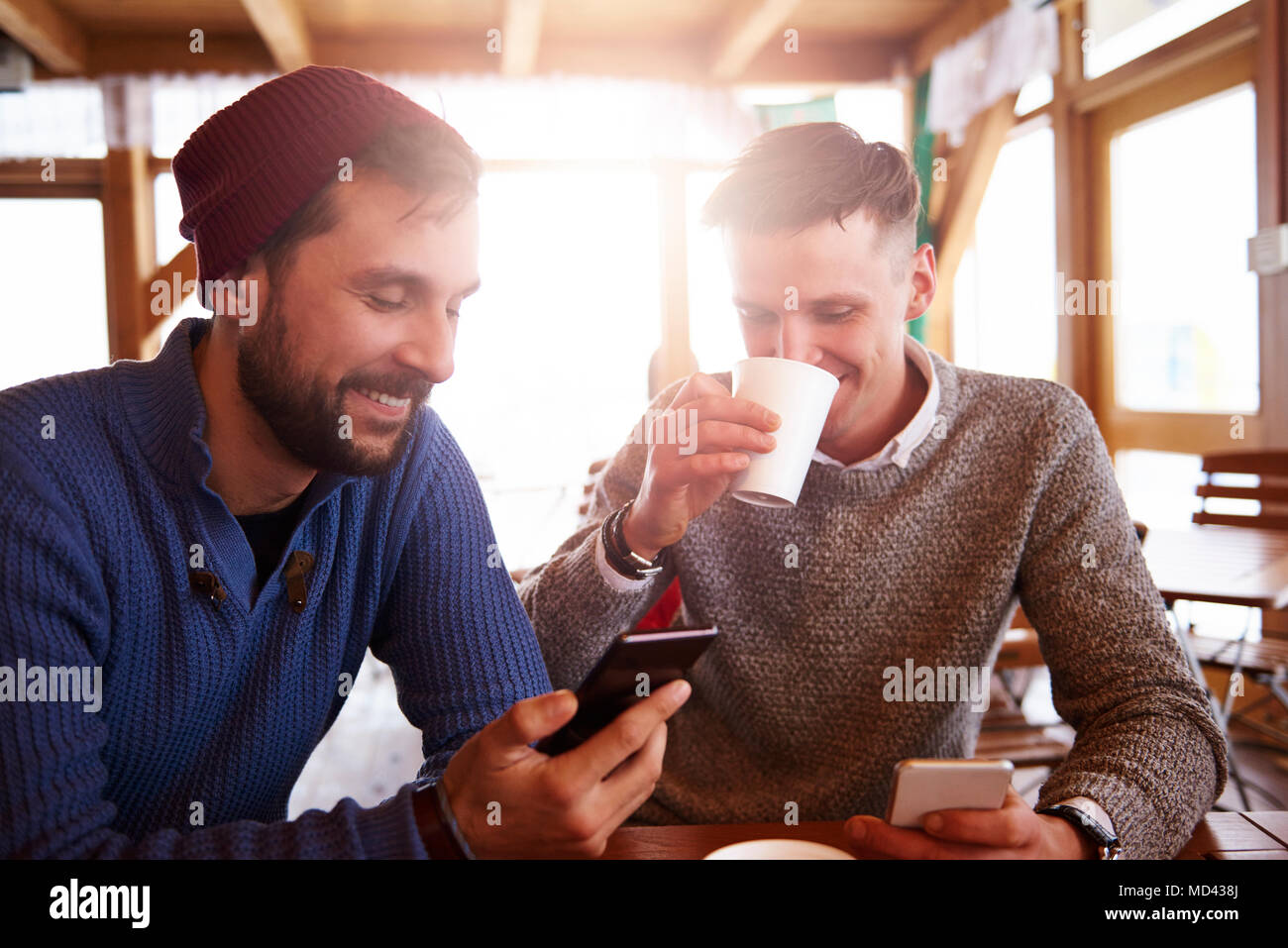 Young men smiling over text message on mobile phones Stock Photo