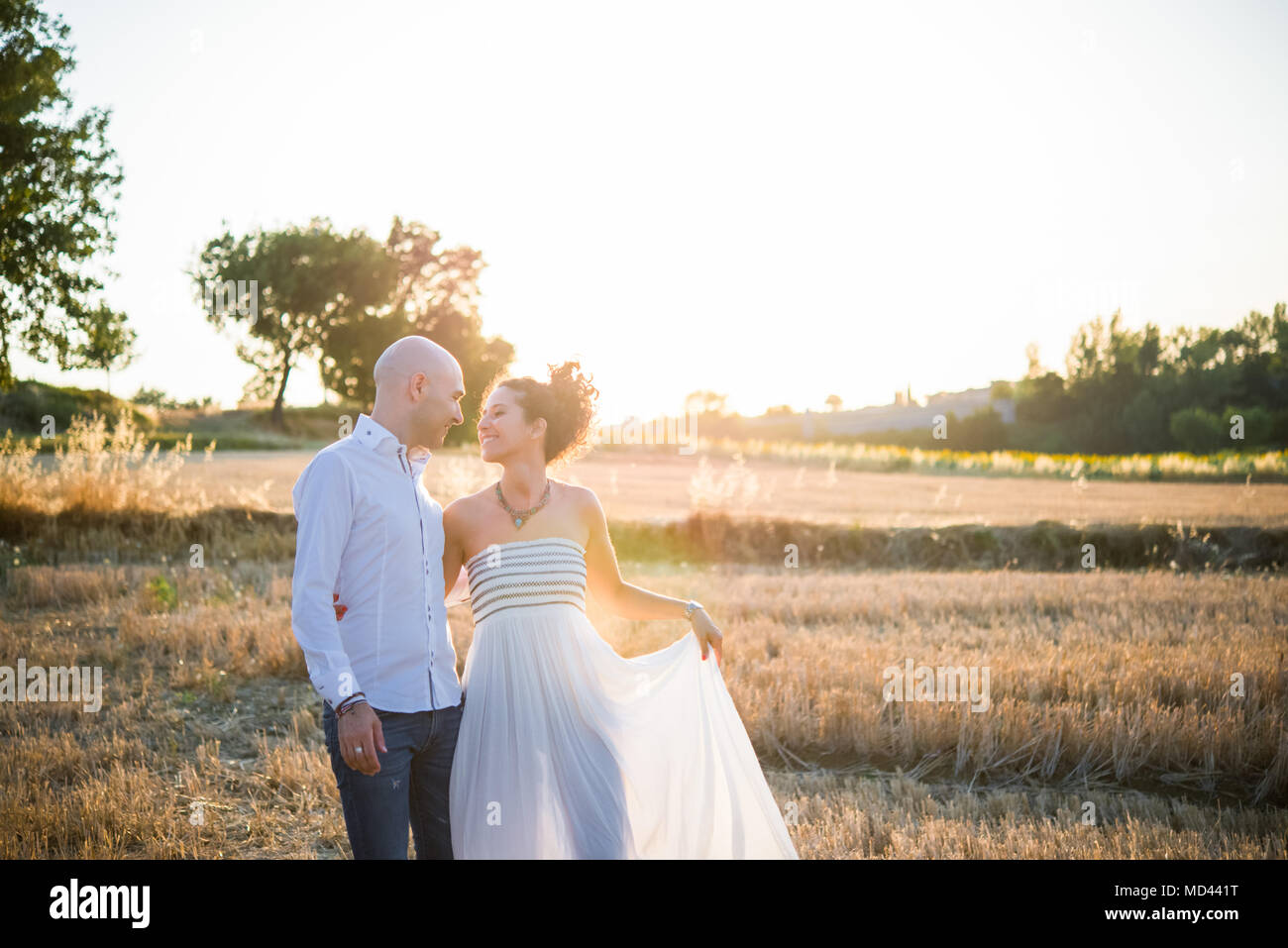 Heterosexual couple standing in field, face to face, smiling Stock Photo