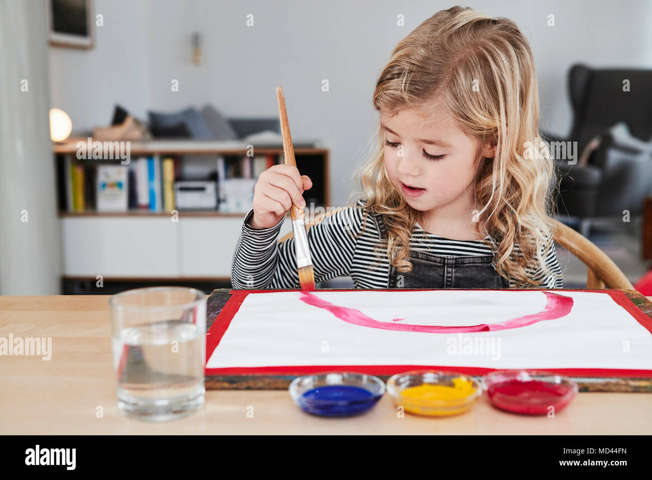 Young girl sitting at table, painting picture Stock Photo