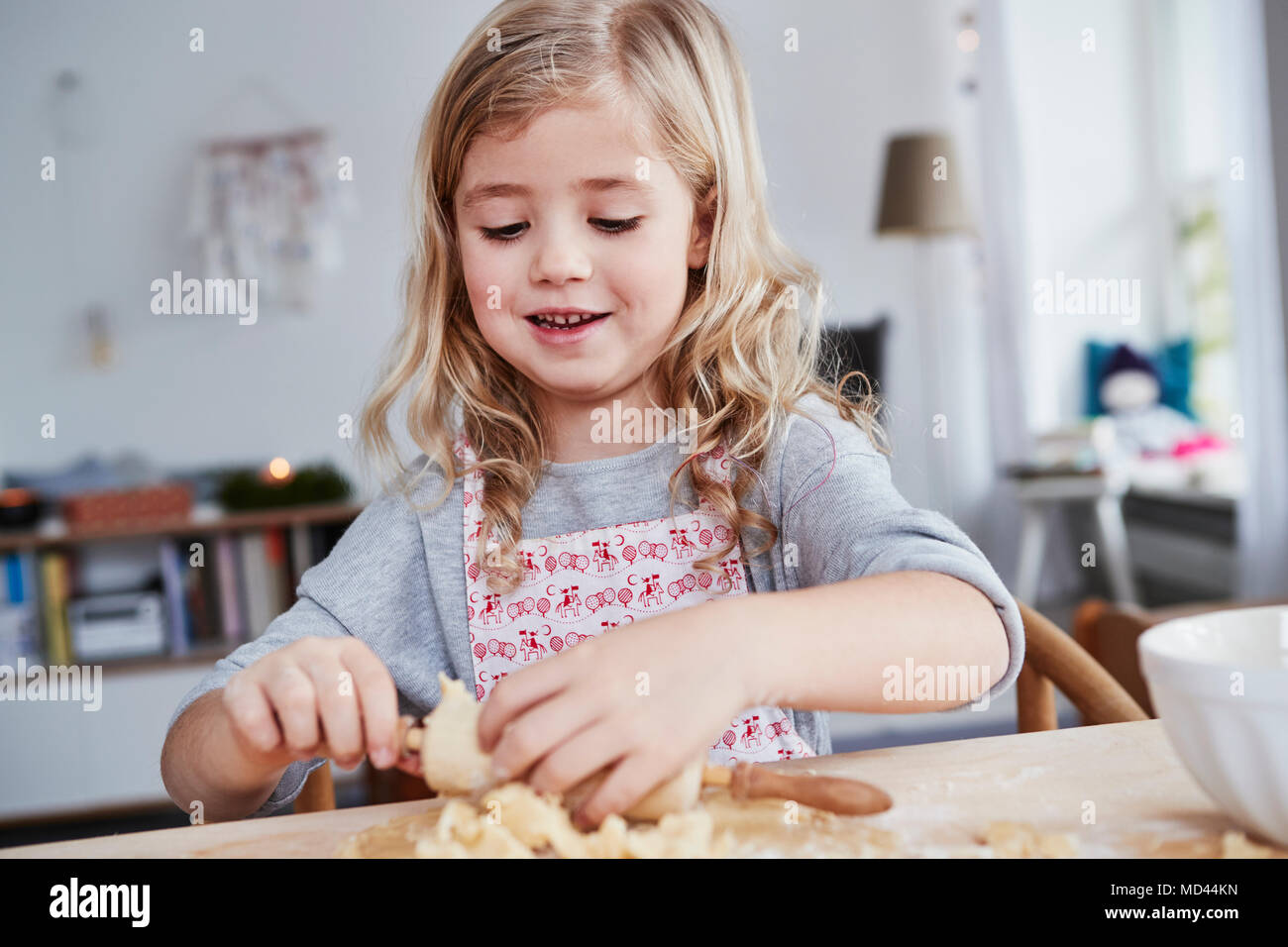 Young girl rolling out cookie dough, dough stuck to rolling pin Stock Photo