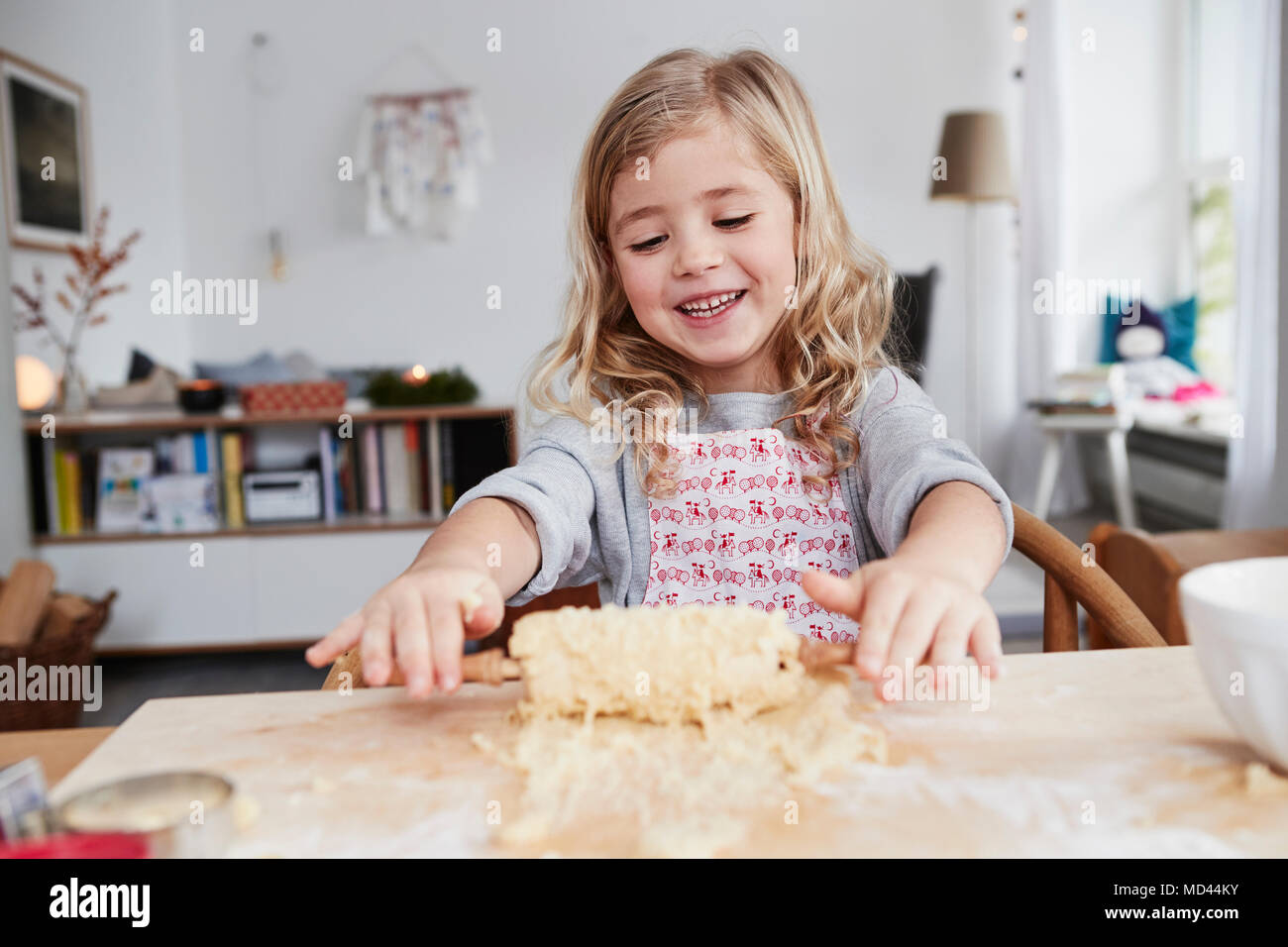 Young girl rolling out cookie dough, dough stuck to rolling pin Stock Photo