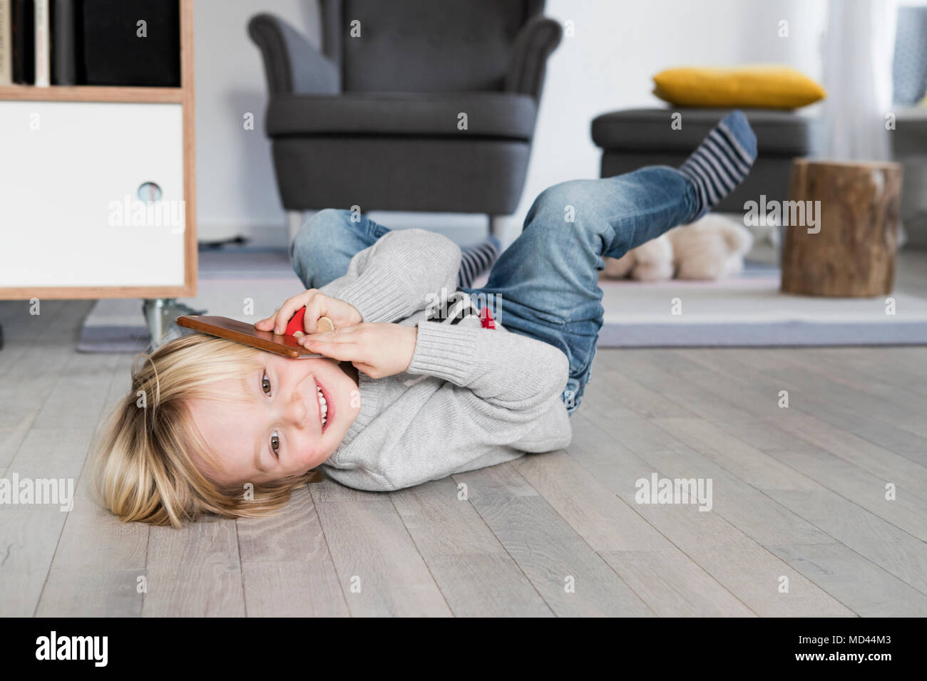 Young boy lying on floor, holding smartphone to ear, smiling Stock Photo