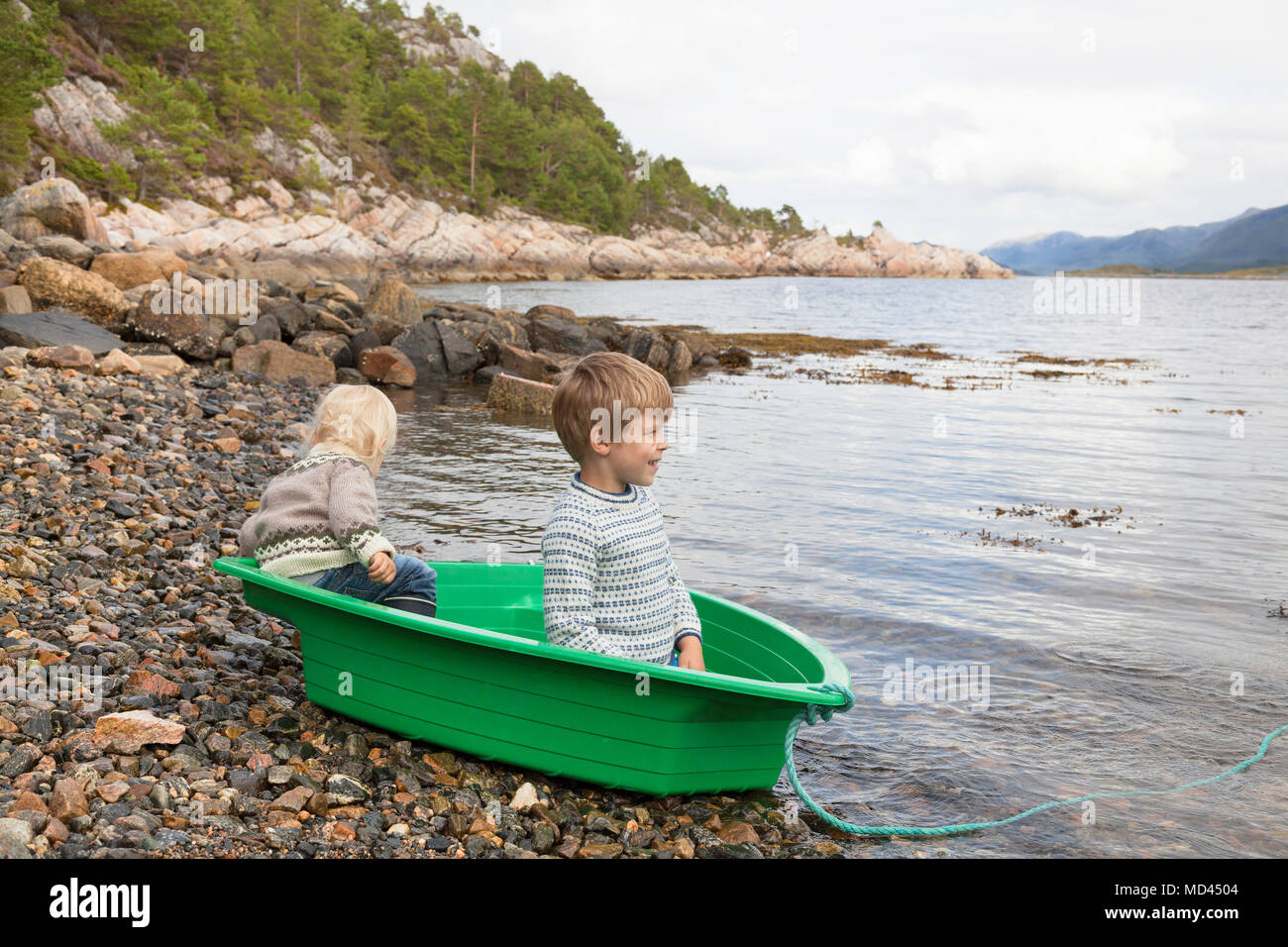 Boys in green boat at fjord water's edge, Aure, More og Romsdal, Norway Stock Photo