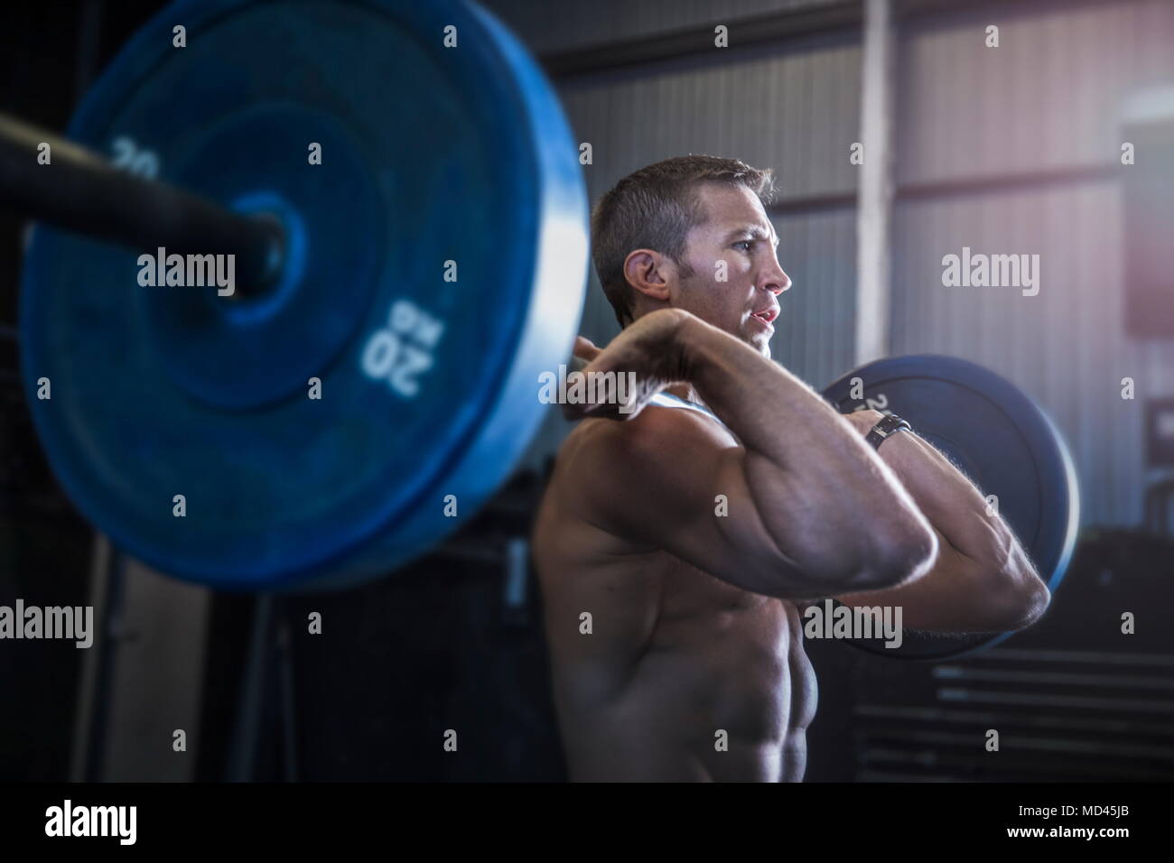 Man exercising in gym, using barbell, front squat position Stock Photo