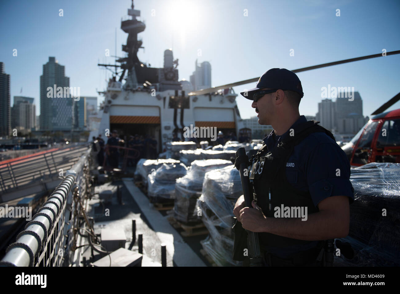 A Coast Guardsman assigned to the Coast Guard Cutter Bertholf stands anti-terrorism/force-protection watch aboard the cutter during an offload at the B Street Pier in San Diego, March 20, 2018. During the offload, the Coast Guard along with state and federal partners, offloaded approximately 36,000 pounds of cocaine interdicted off the coasts of Central and South America by five Coast Guard cutters between early February and early March. (U.S. Coast Guard photo by Petty Officer 3rd Class Sarah Wilson/released) Stock Photo