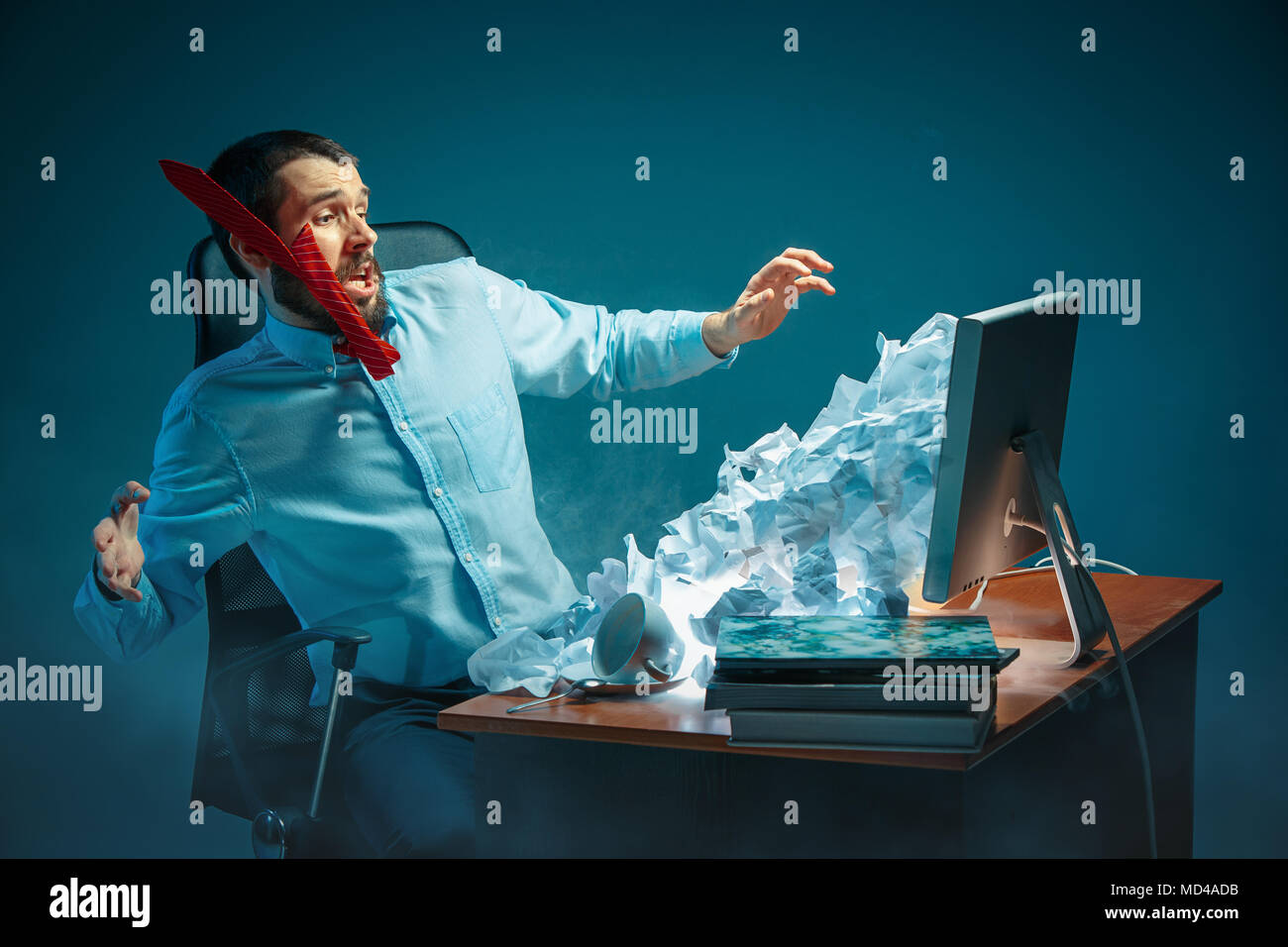 Young stressed handsome businessman working at desk in modern office shouting at laptop screen and being angry about spam Stock Photo