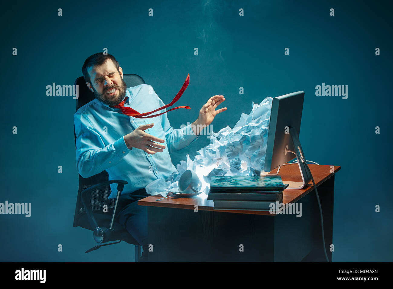 Young stressed handsome businessman working at desk in modern office shouting at laptop screen and being angry about spam Stock Photo