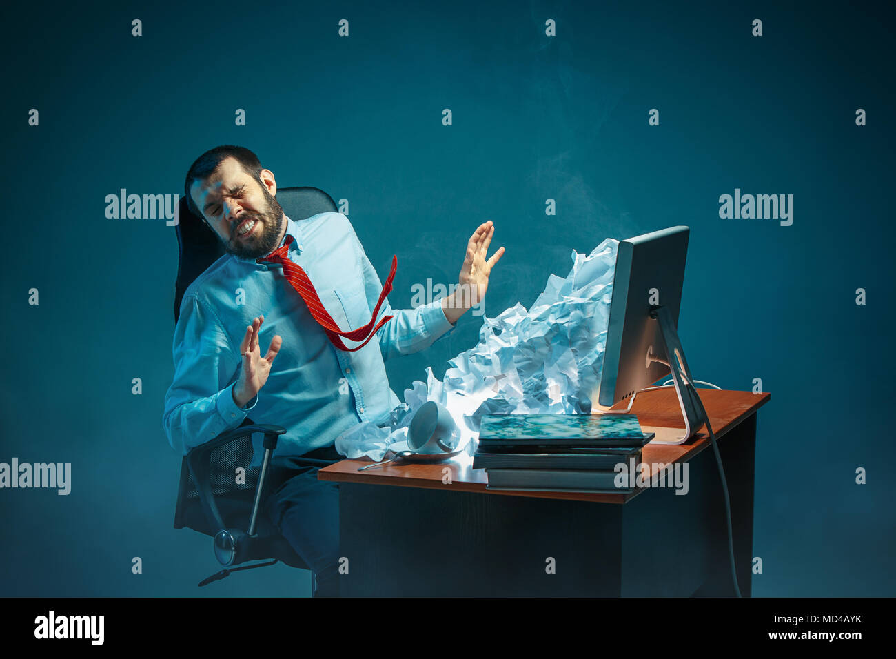 Young stressed handsome businessman working at desk in modern office shouting at laptop screen and being angry about spam Stock Photo