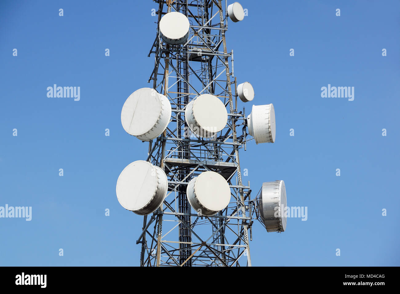 Mobile phone communication antenna tower with satellite dish on blue sky background, Telecommunication tower Stock Photo