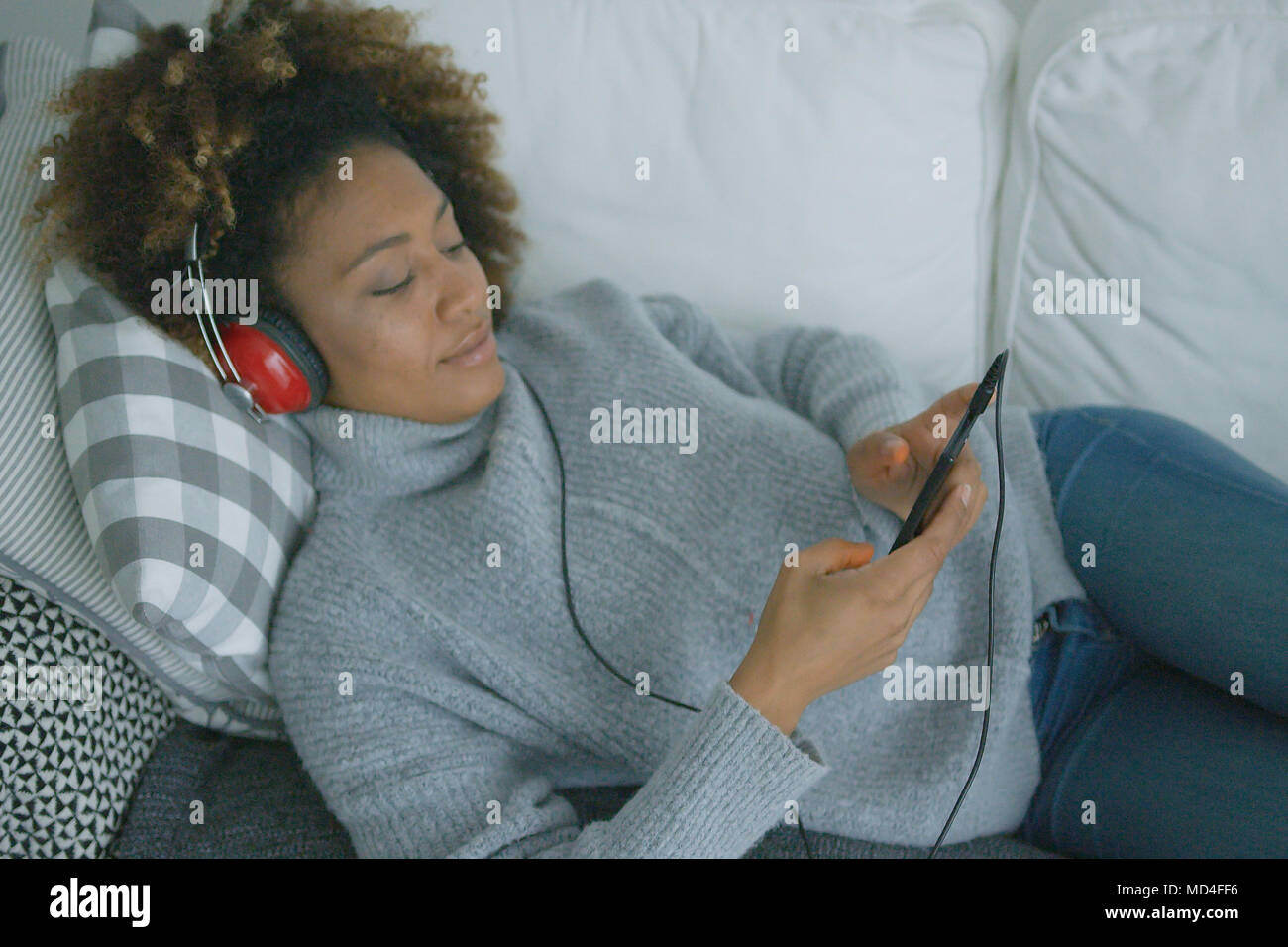 Young woman chilling on sofa with gadgets Stock Photo - Alamy