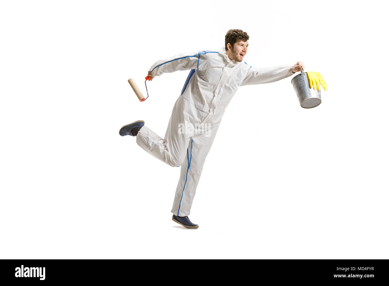 Young male decorator painting with a paint roller climbed a ladder