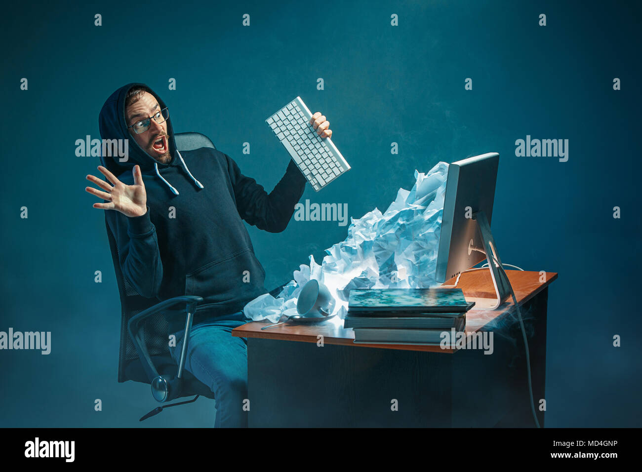 Young stressed handsome businessman working at desk in modern office shouting at laptop screen and being angry about spam Stock Photo