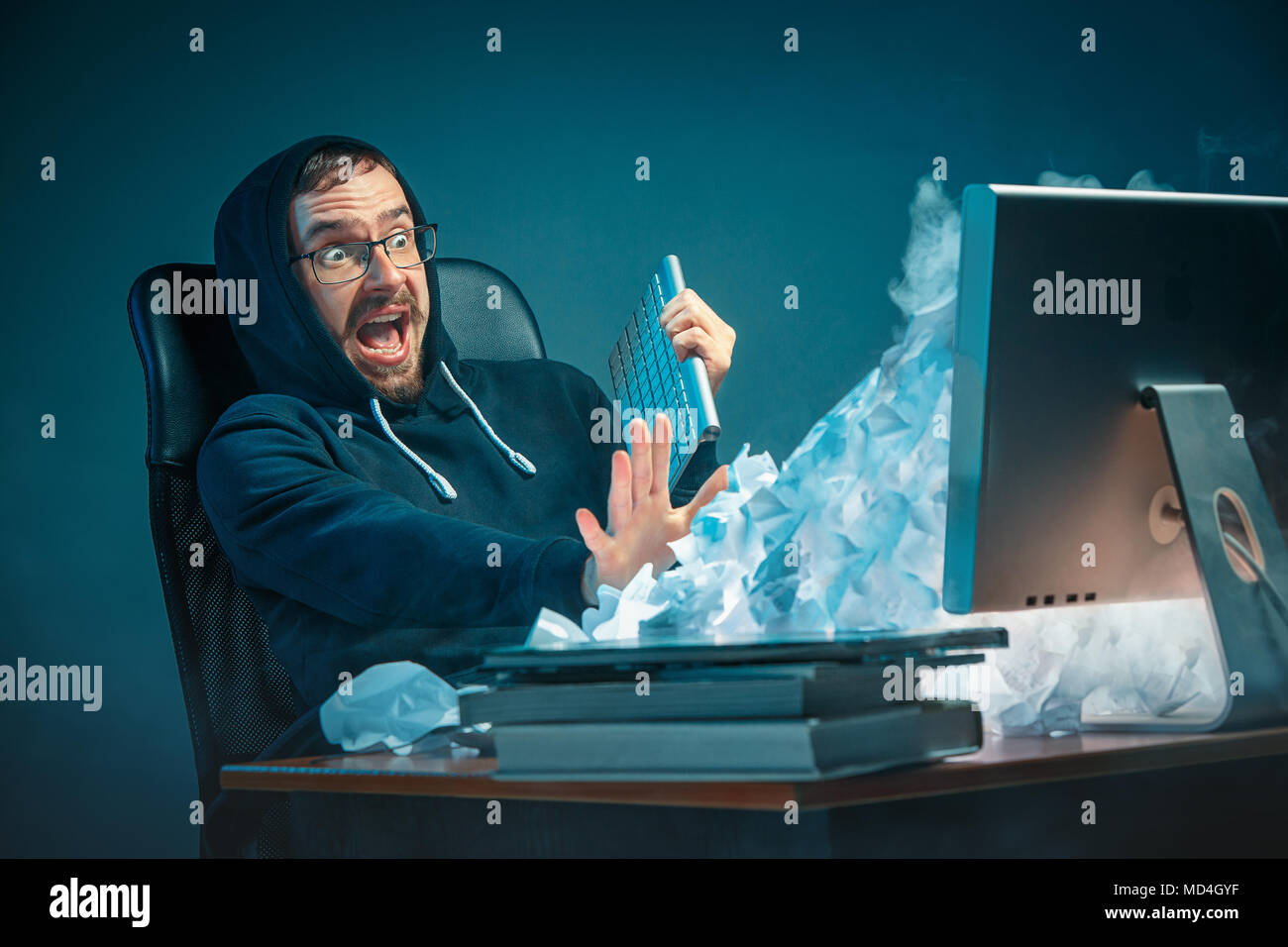 Young stressed handsome businessman working at desk in modern office shouting at laptop screen and being angry about spam Stock Photo