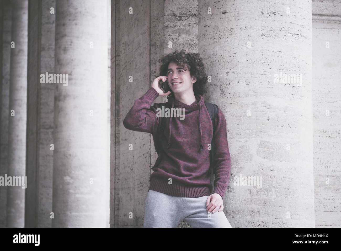 Handsome young man with curly hair in tracksuit talking on his mobile phone. Vintage looking image Stock Photo