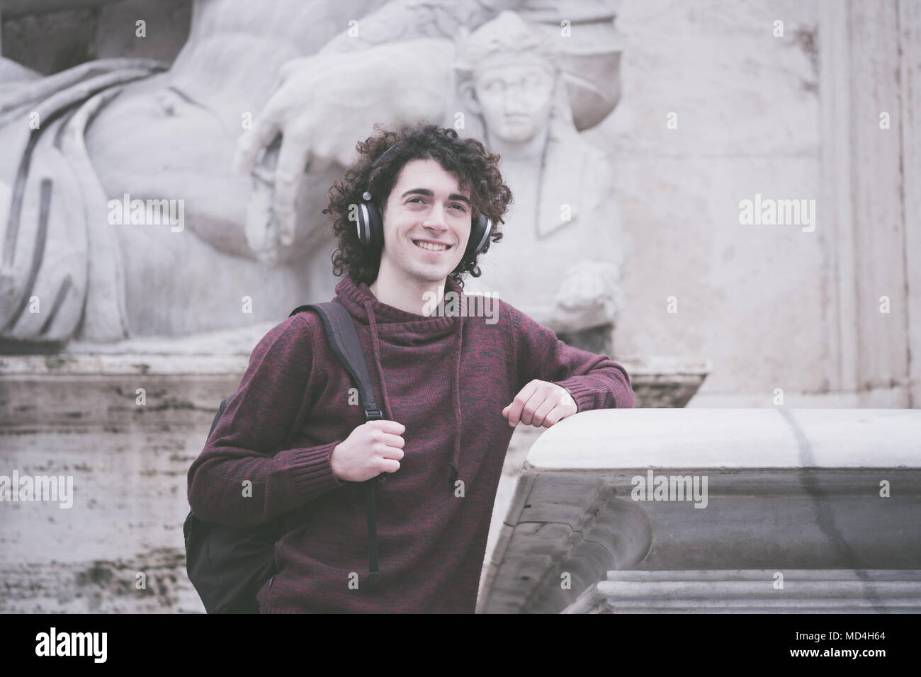Vintage looking image of handsome young man with curly hair and headphones on his head listening the music Stock Photo