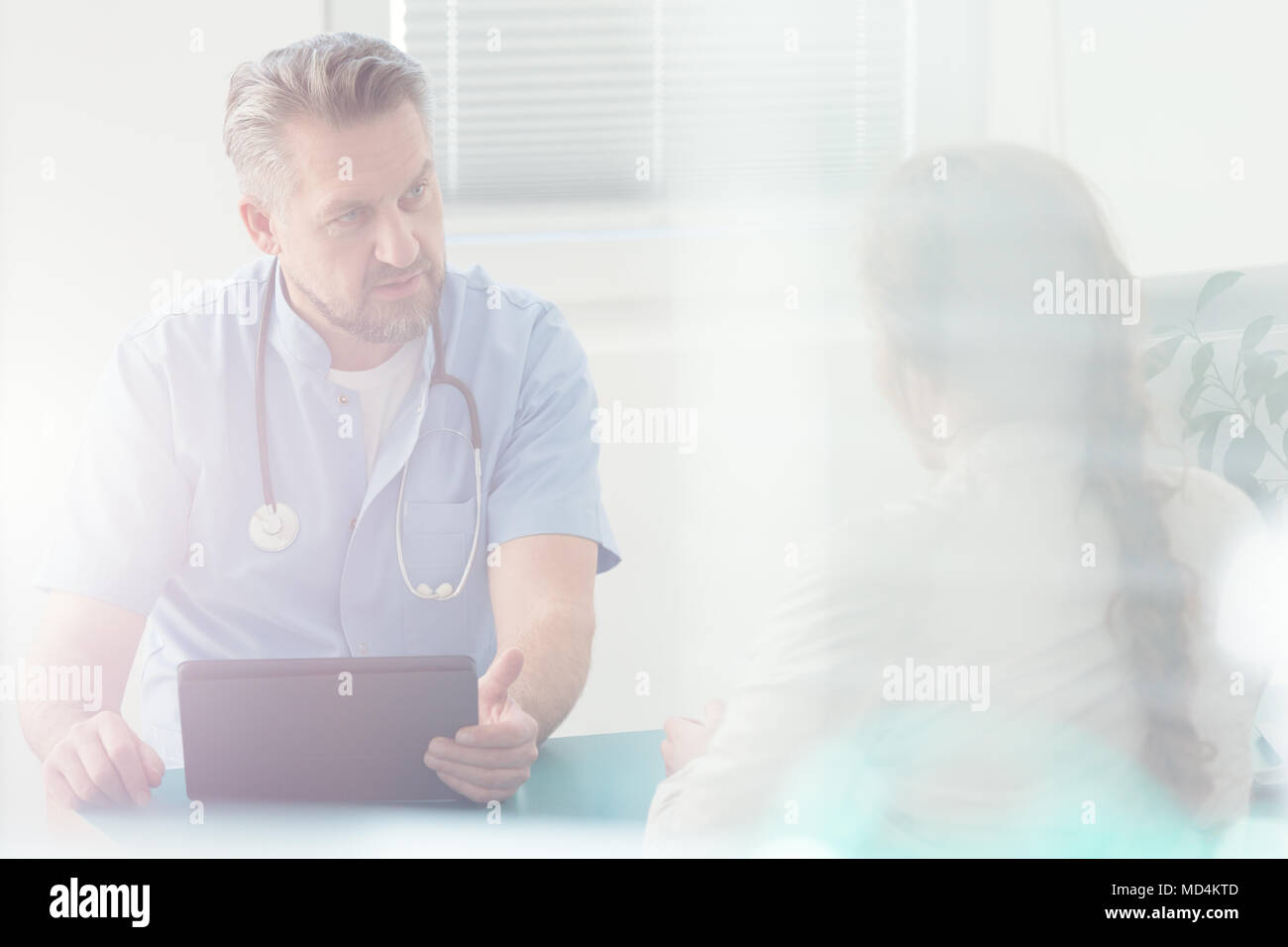 Serious doctor discussing a disease with his patient in hospital Stock Photo