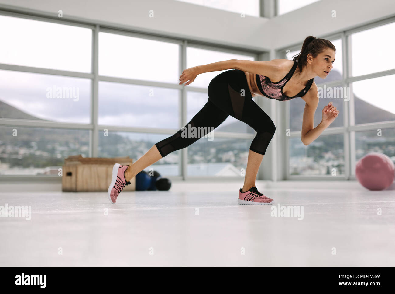 Caucasian woman working out in gym. Young female in a stretching pose at fitness studio. Stock Photo