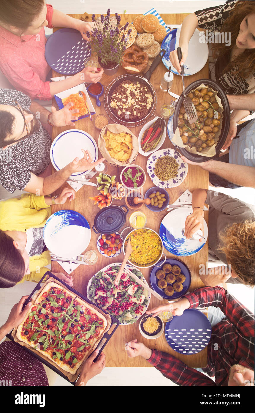 People sitting at a table full of vegetarian food such as falafel, pasta or bulgur Stock Photo