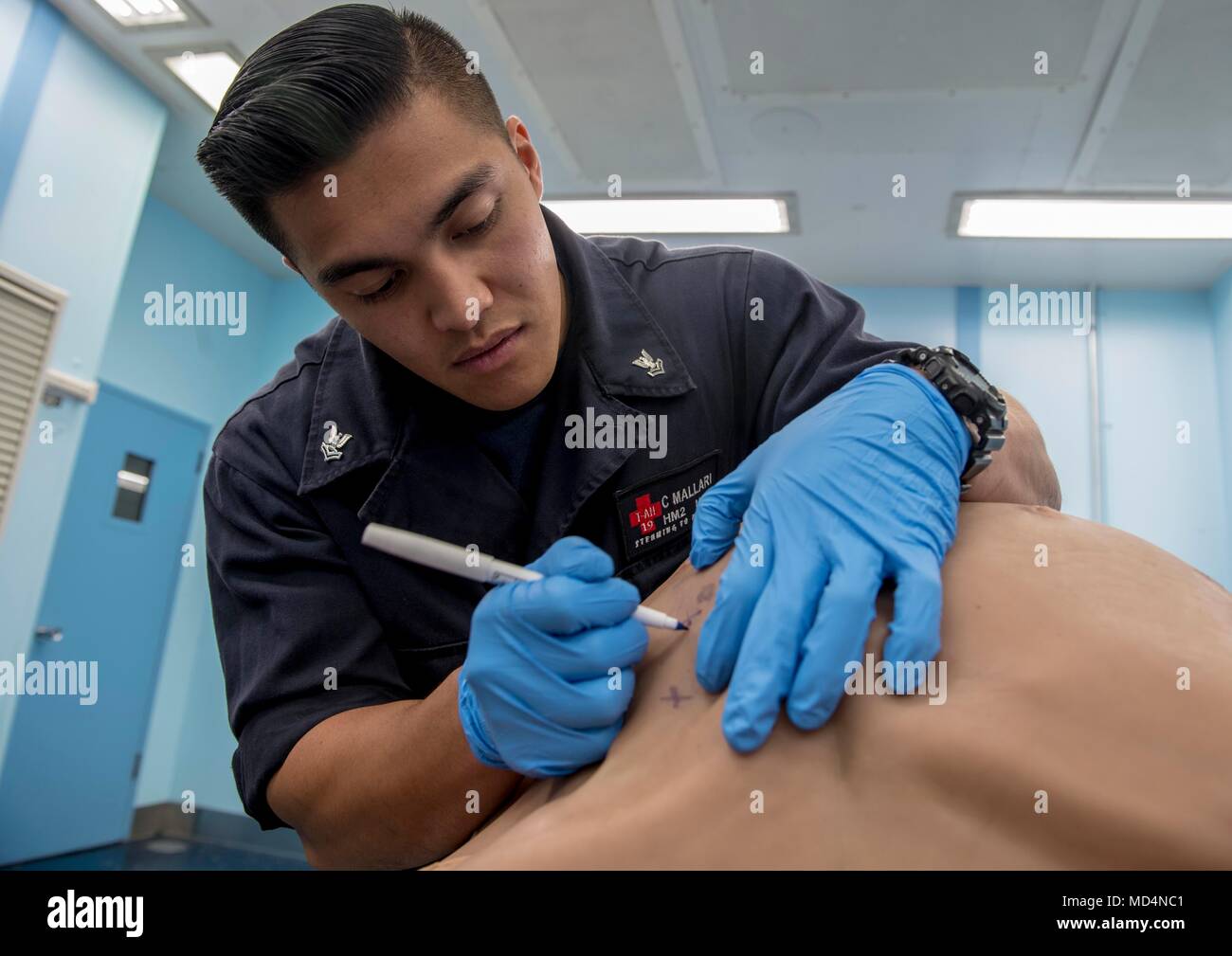 180323-N-RM689-0130 PACIFIC OCEAN (March 23, 2018) Hospital Corpsman 2nd  Class Christian Mallari, from Dededo, Guam, uses a pen to mark where an  incision will be during a tele-procedural mentorship scenario that will, image size:1300x1009