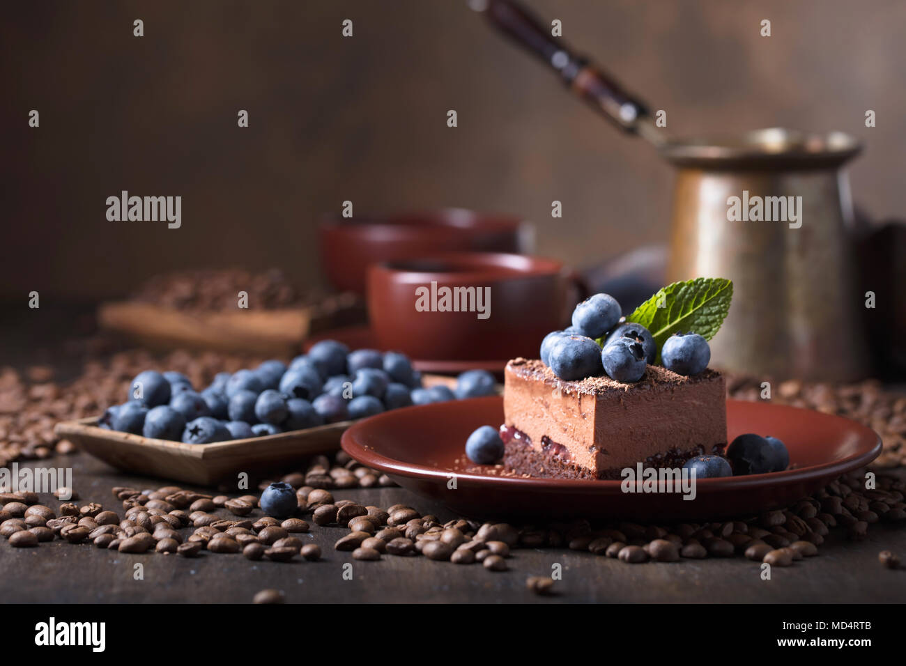 Chocolate cake with blueberries and mint on a brown plate. Copy space ...
