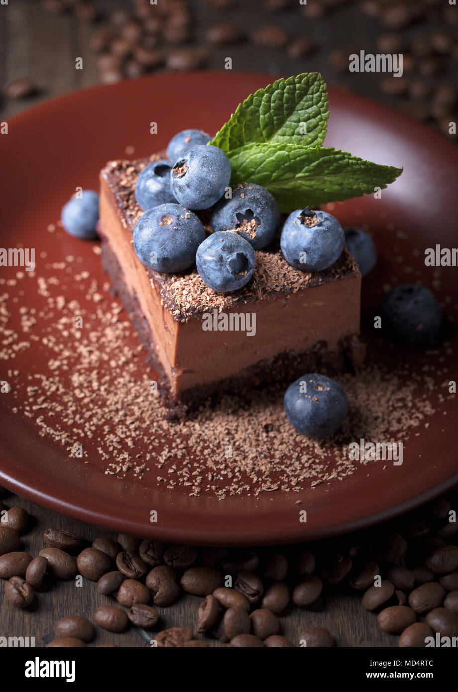 Chocolate cake with blueberries and mint on a brown plate Stock Photo ...