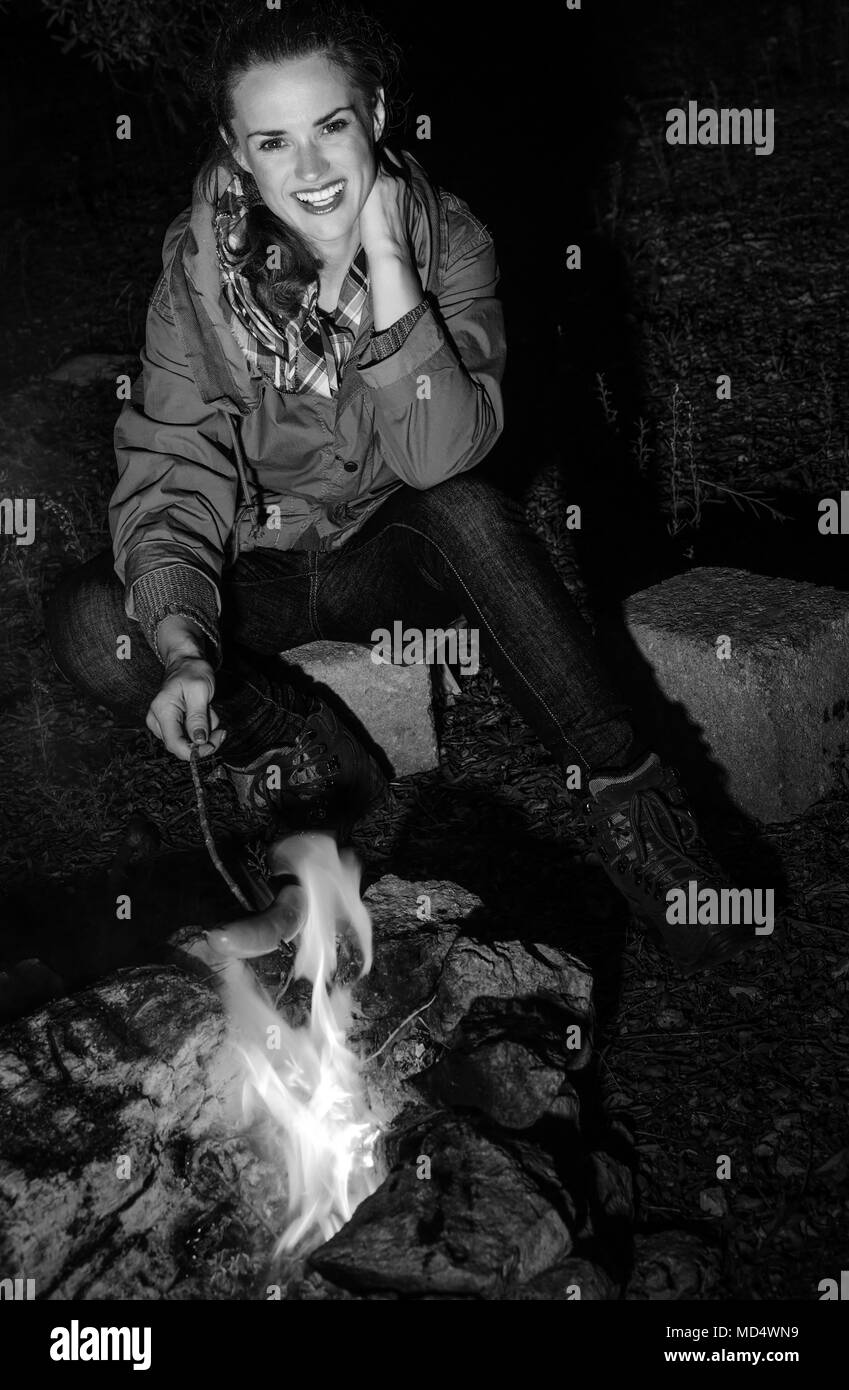 Into the wild. smiling tourist woman near a campfire grilling sausages Stock Photo