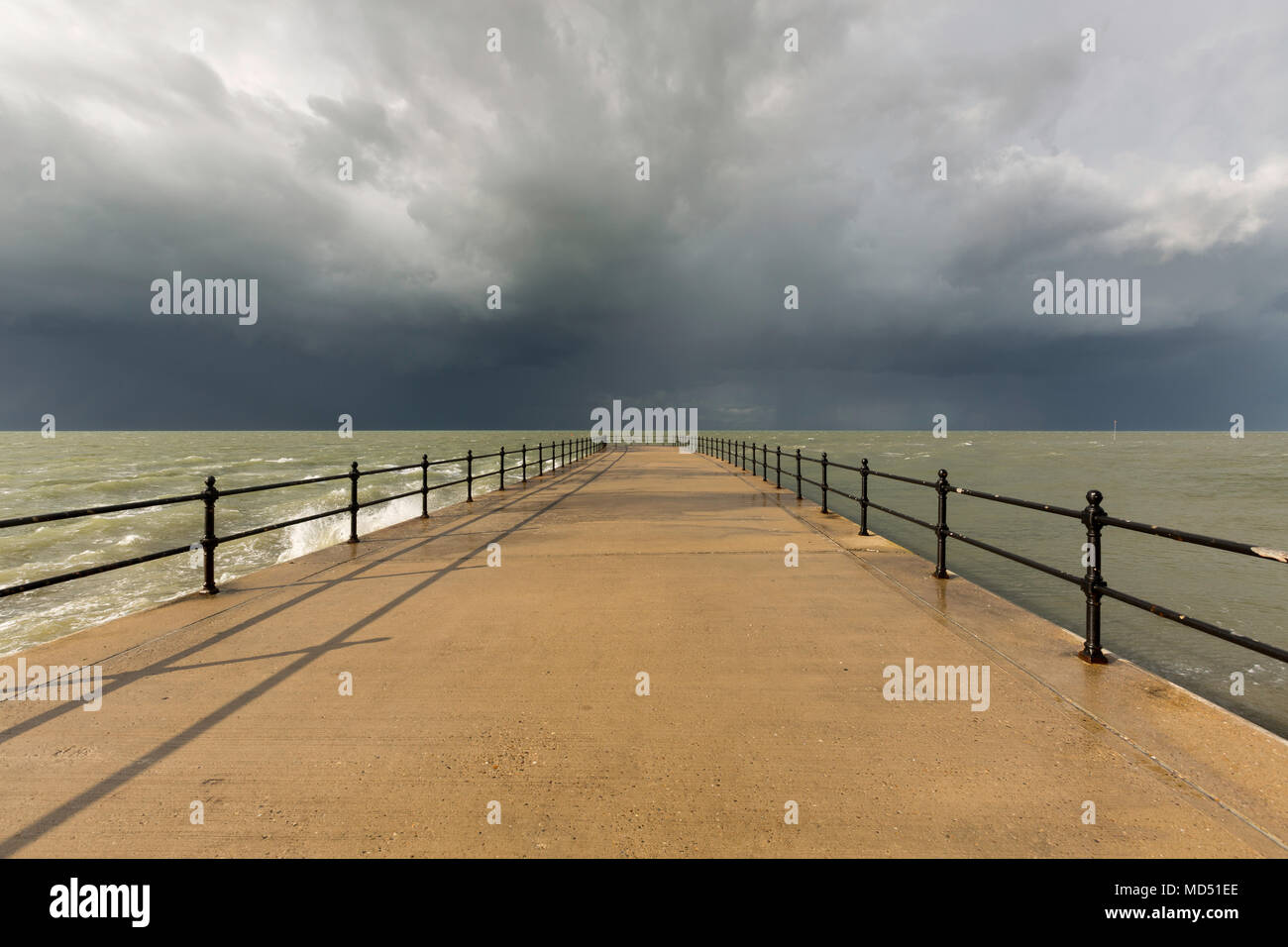 Dramatic storm clouds and long shadows at Hampton Pier, Herne Bay on the North Kent coast, UK. Stock Photo