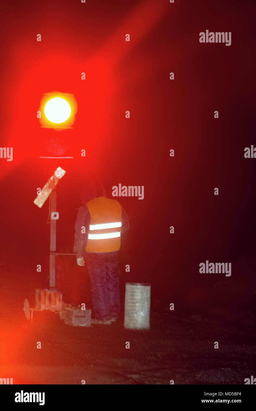 Repair work on road at night and traffic light manual control. Road