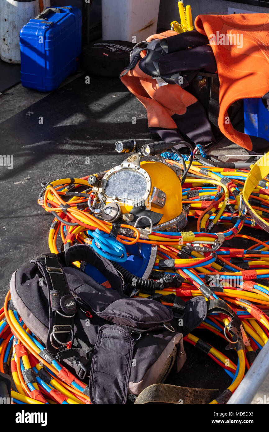 Professional diver's full faced helmet, with hookah and communication cables, on the deck of a boat Stock Photo