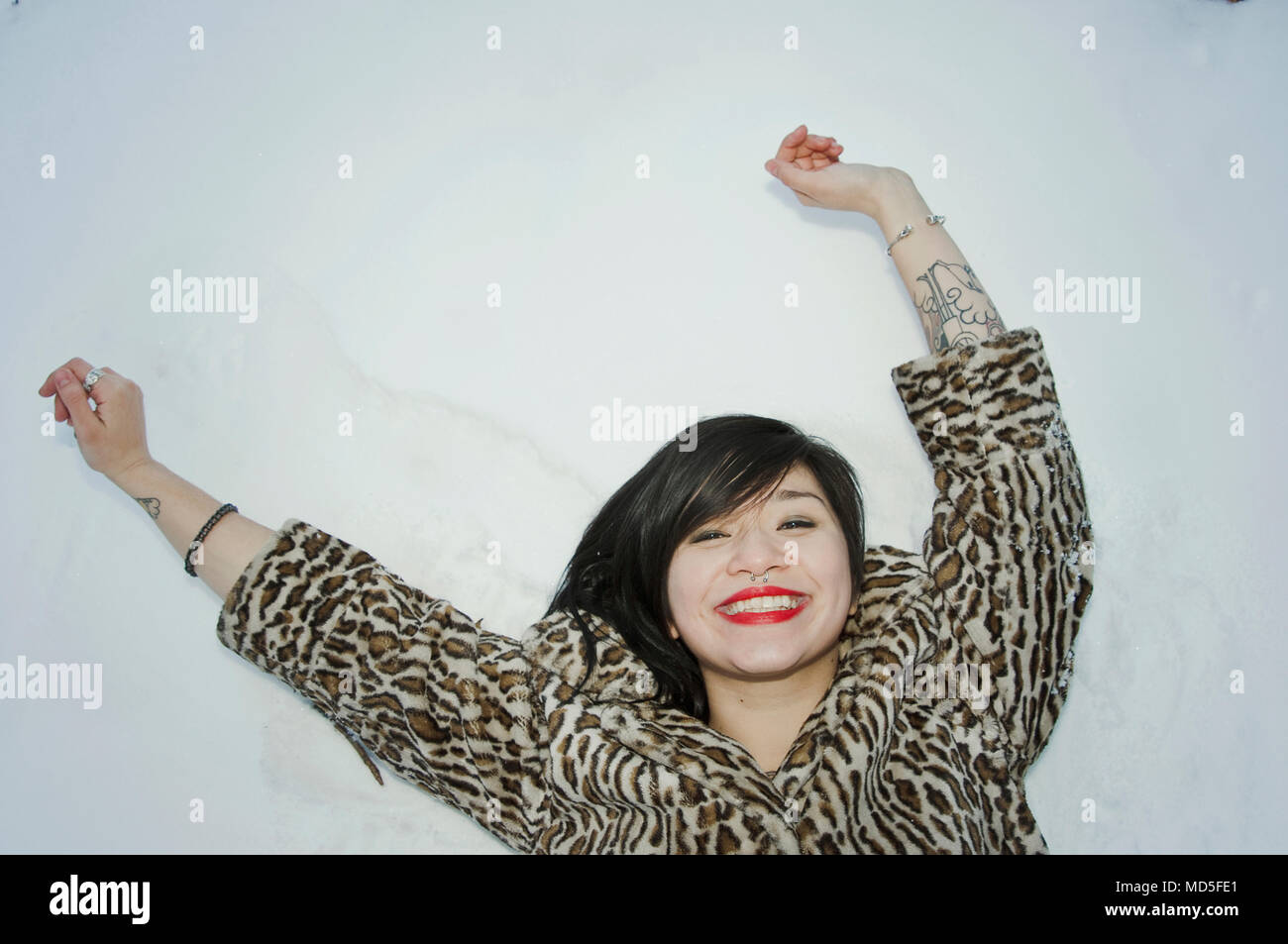 A woman laying down in the snow smiling. Stock Photo