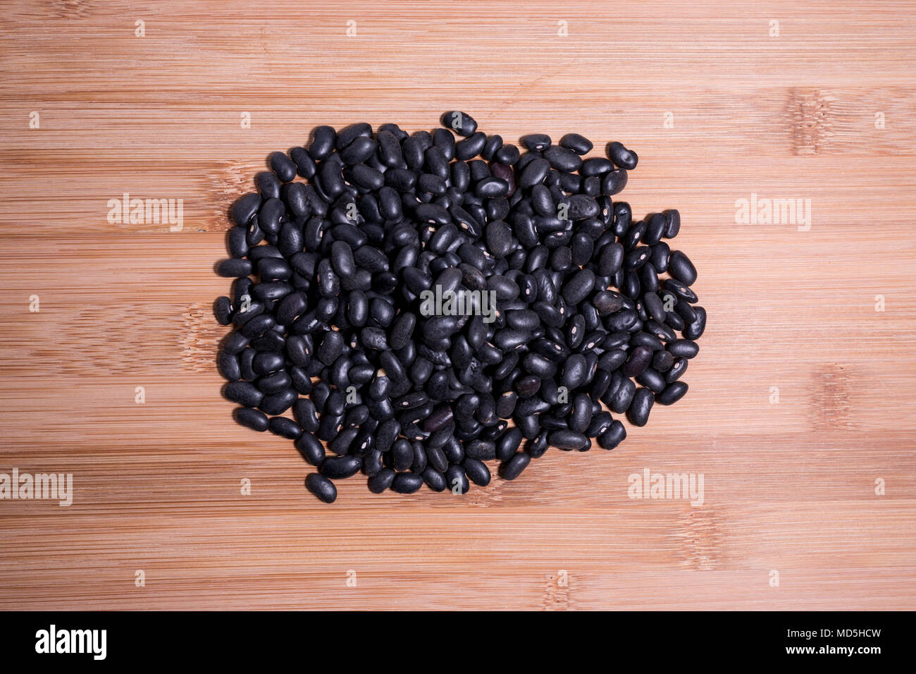 Raw dry uncooked black beans on natural wood table surface. Black beans