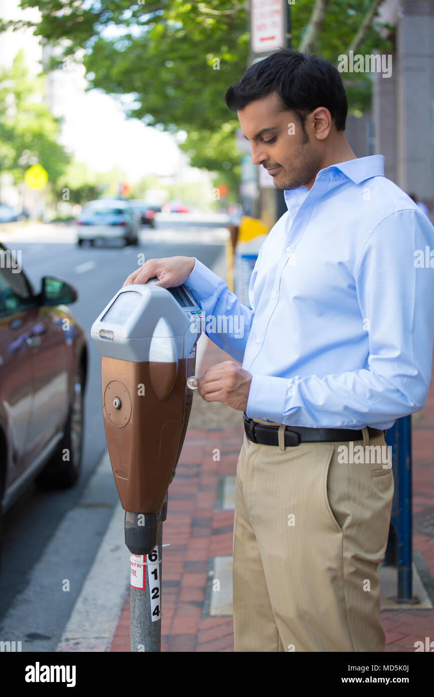 Closeup portrait, young man putting coins in parking meter outside to
