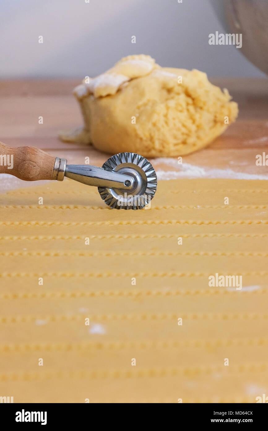 pastry cutter wheel cuts a layer of puff pastry in the backgroung a raw dough with flour in the foreground lines of pastry out focus Stock Photo Alamy