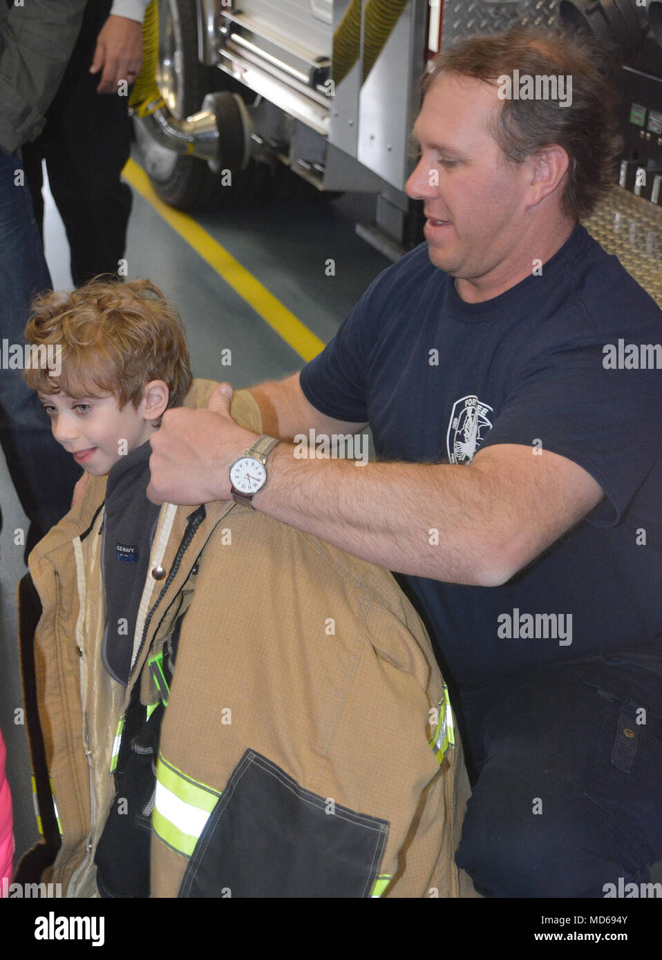 Fort Lee Firefighter Jim Hazlitt helps Michael Lambeth, a student from Harrison Elementary, try on a firefighter’s jacket to show him how heavy the suit is. Children from the K-5 special education program at Harrison Elementary in the Prince George School District toured Fire Station No. 2 March 26. Several firefighters were on hand to show the students firetrucks, ambulances and fire-fighting gear. (Photo by Amy Perry, Fort Lee Public Affairs) Stock Photo